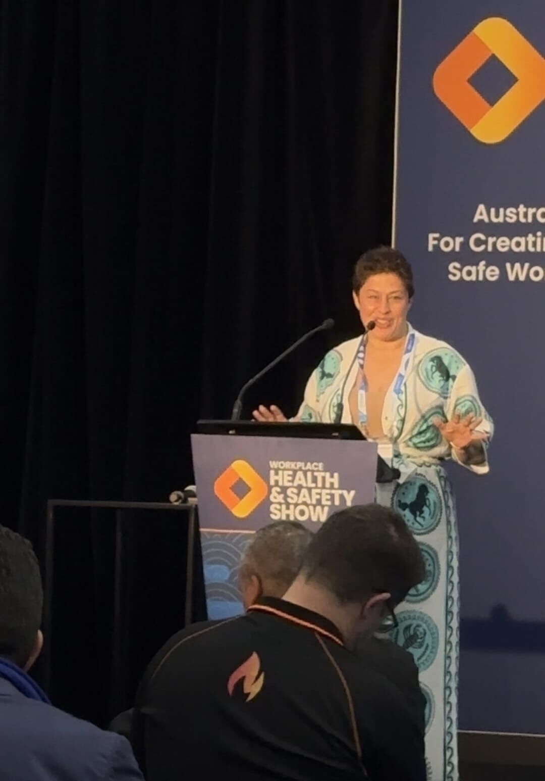 Amanda Anderson smiling and gesturing at the Workplace Health & Safety Show podium